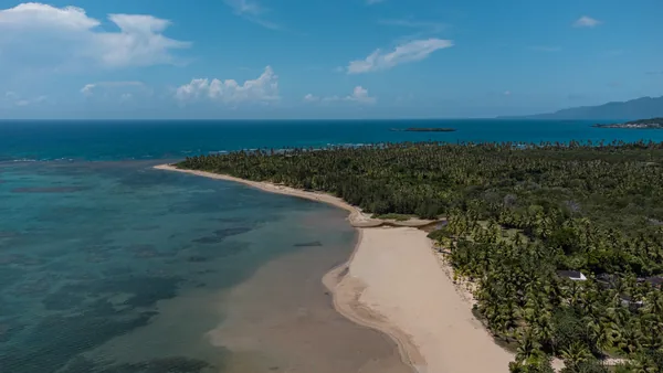 Playa El Estillero desde el aire: arco de arena, arrecife y cocoteral