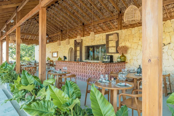 La sala de Olea: techo de cana, lámparas de mimbre, barra de celosía y mesas de madera
