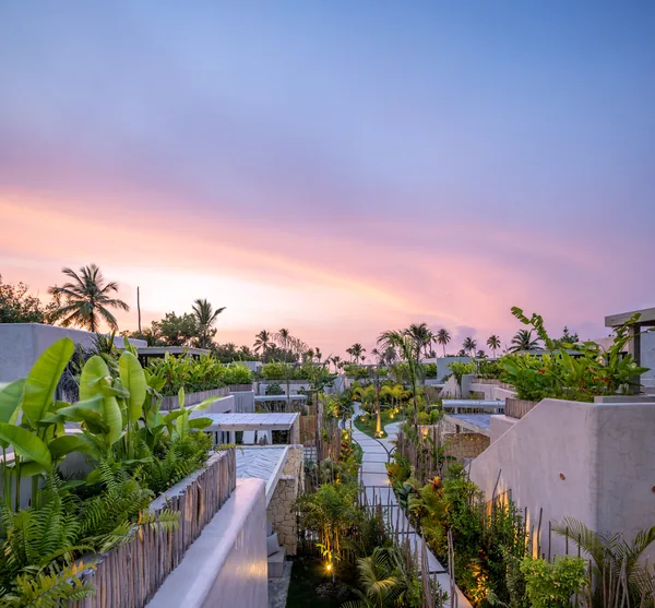 Puesta de sol rosa sobre las villas y el sendero hacia el mar